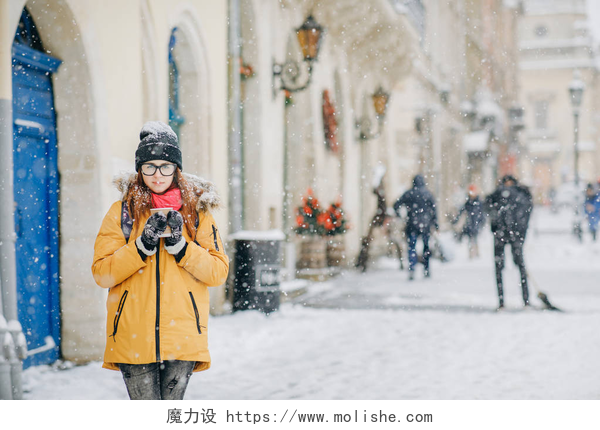 在国外的大道上白雪皑皑的地面有一个美女在拍照美丽快乐的女人走在城市周围喝咖啡在冬天的城市